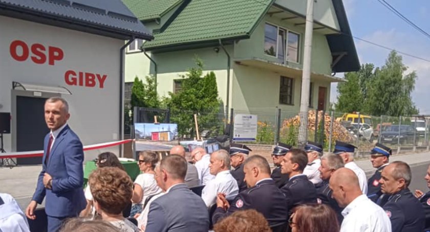 Zdjęcie uczestników uroczystości siedzących przed budynkiem remizy w Gibach