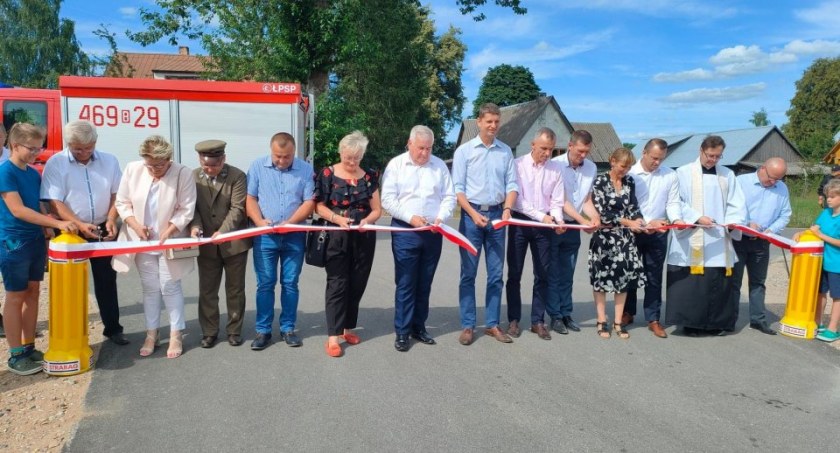 Zdjęcie osób przecinających wstęgę nad wyremontowaną drogą asfaltową