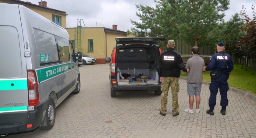 Zdjęcie funkcjonariuszy z zatrzymanym na placu za placówką SG w Sejnach