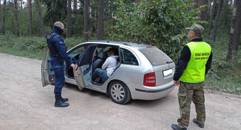 Zdjęcie policjanta i pogranicznika stojących przy zatrzymanej skodzie 