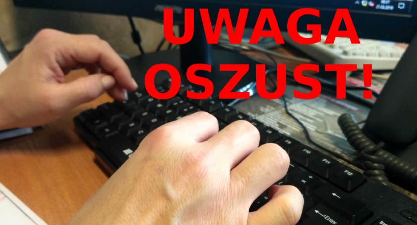 Zdjęcie dłoni osoby piszącej na klawiaturze z ostrzegawczym napisem 