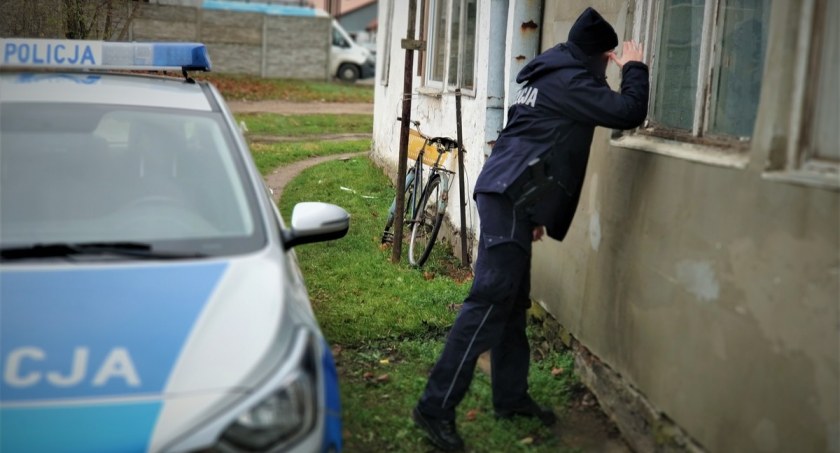 Zdjęcie policjanta zaglądającego w okno starego domu