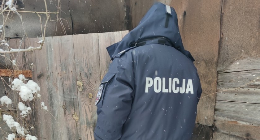 Zdjęcie policjanta wchodzącego przez drzwi drewnianego domu