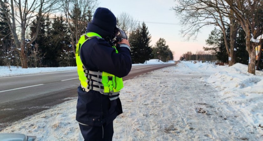 Zdjęcie policjanta z miernikiem prędkości na tle zimowego otoczenia