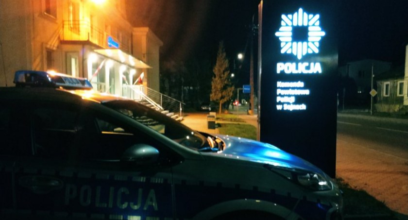 Zdjęcie komendy i zaparkowanego przy niej radiowozu po zmroku