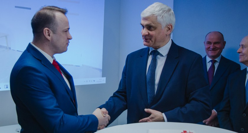 Zdjęcie wójta gminy Giby i wojewody podlaskiego w uścisku dłoni po podpisaniu umowy