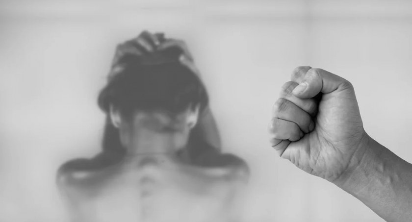 Zdjęcie zaciśniętej pięści i postaci trzymającej się za głowę w odruchu obronnym