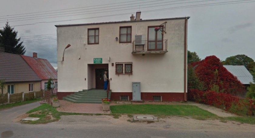 Zdjęcie murowanego piętrowego budynku w otoczeniu parterowych domów