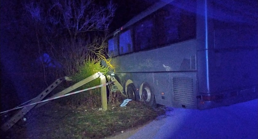 Zdjęcie wykonane pzez OSP Berżniki, przedstawia autobus stojący w poprzek pobocza przy złamanym słupie, oświetlony reflektorem w zmroku