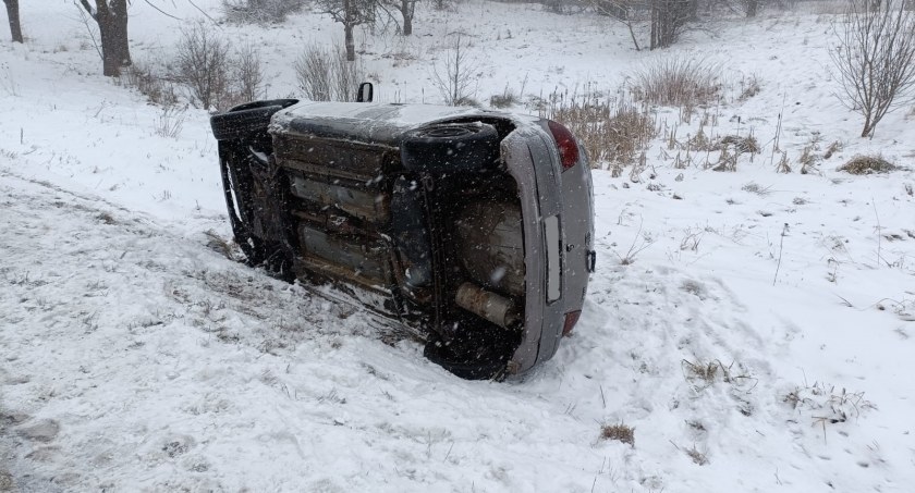 Zdjęcie z miejsca kolizji, przedstawiające auto leżąca poza jednią
