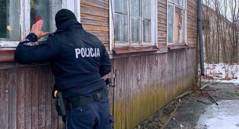Zdjęcie policjanta zaglądającego w okno starego domu