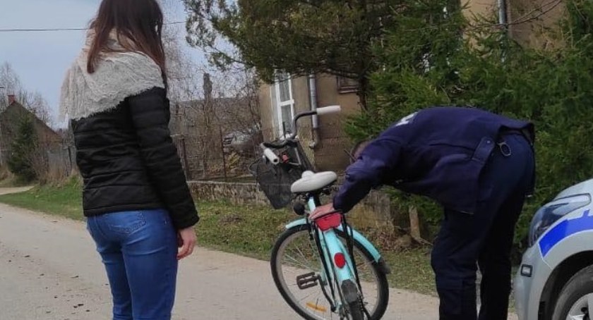 Zdjęcie kobiety obserwującej policjanta nanoszącego znaki na ramę roweru
