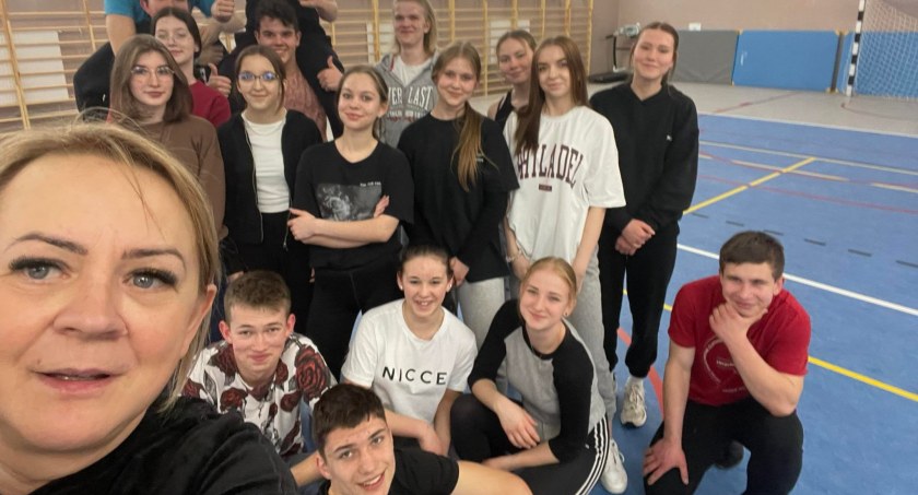 Zdjęcie grupy osób pozujących na sali sportowej szkoły