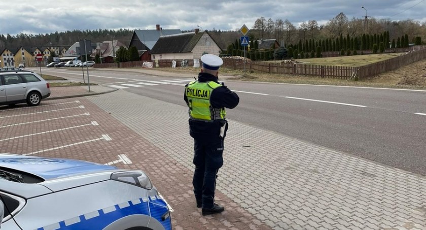 Zdjęcie policjanta w mundurze na skraju parkingu w Gibach