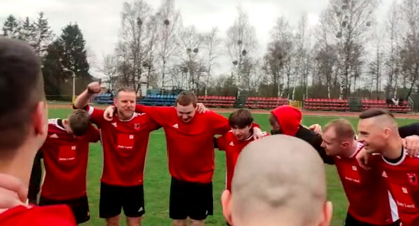 Zdjęcie mężczyzn w czerwonych strojach piłkarskich, stojących w kręgu na boisku