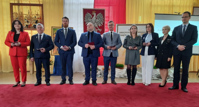 Zdjęcie osób pozujących na tle godła RP